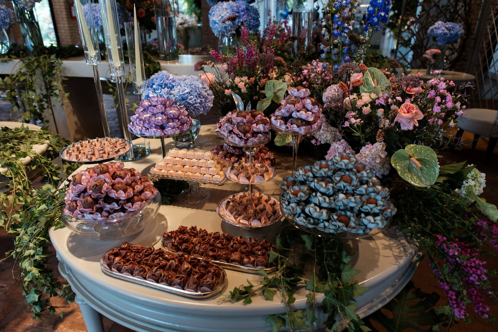 Mesa de doces artesanais Lebbeke com forminhas coloridas e composição floral