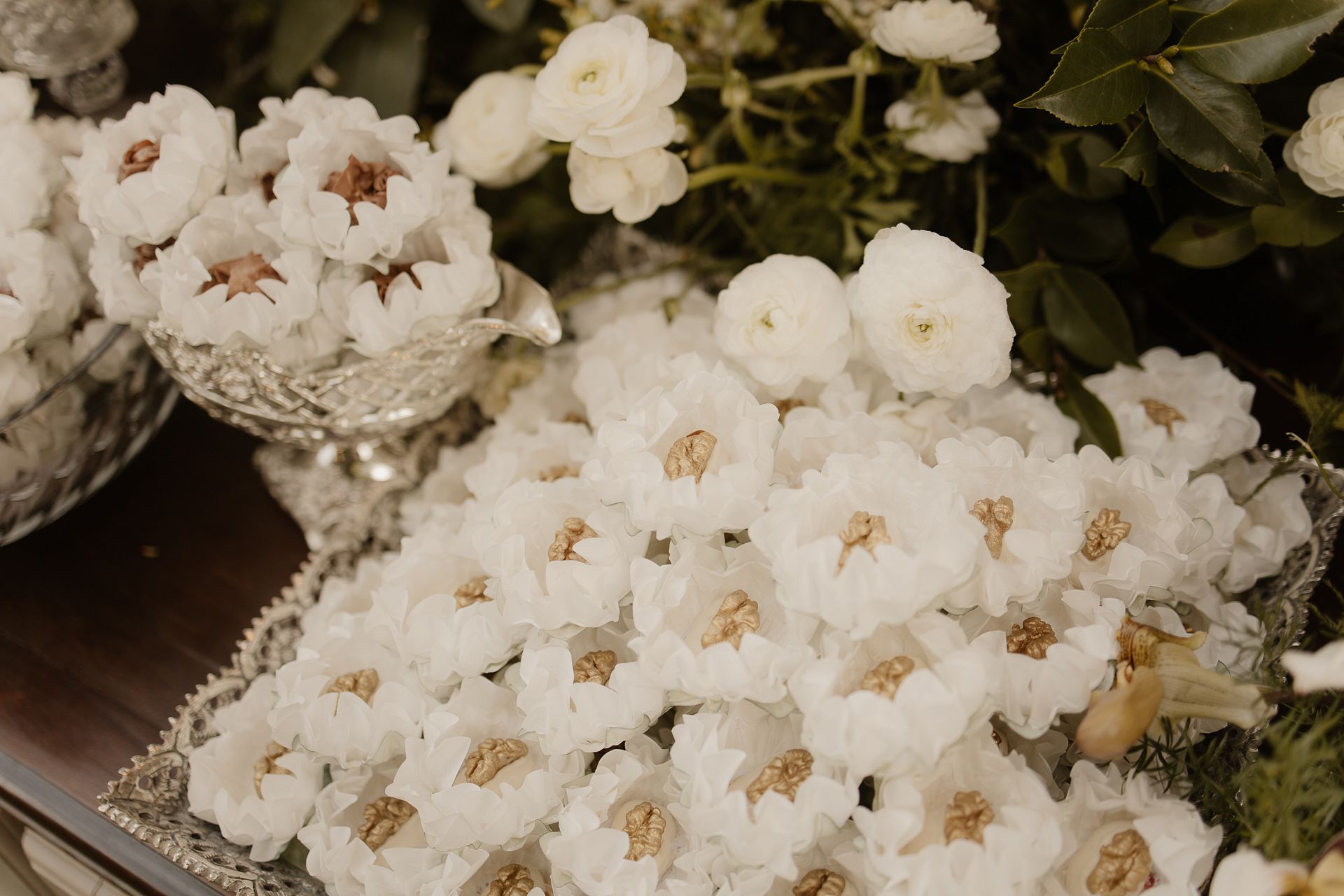 Bombons em forminhas brancas com nozes douradas e flores