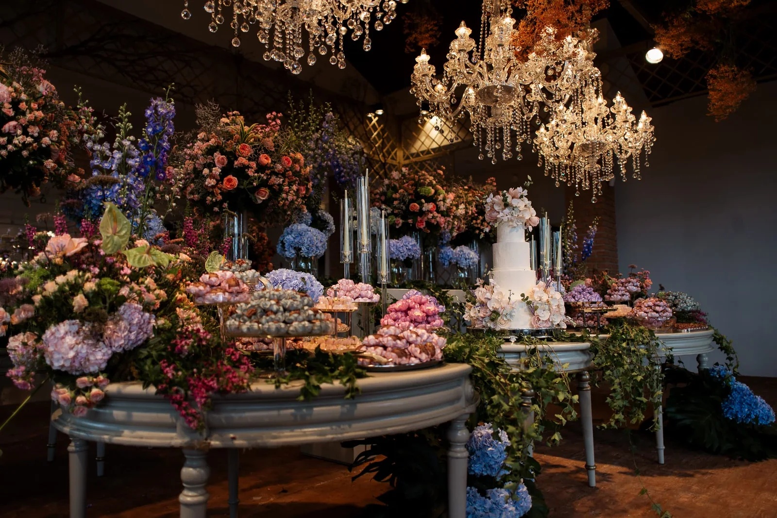 Lebbeke fine sweets dessert table at a wedding reception with cake and flower arrangements