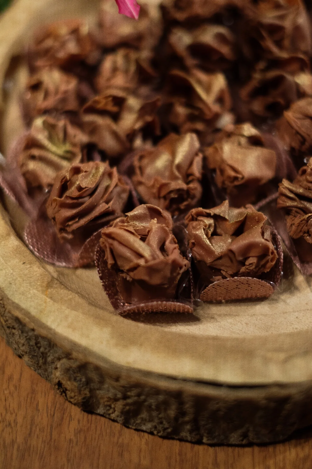 Gourmet brigadeiros in pearlescent cups on a rustic wood surface.
