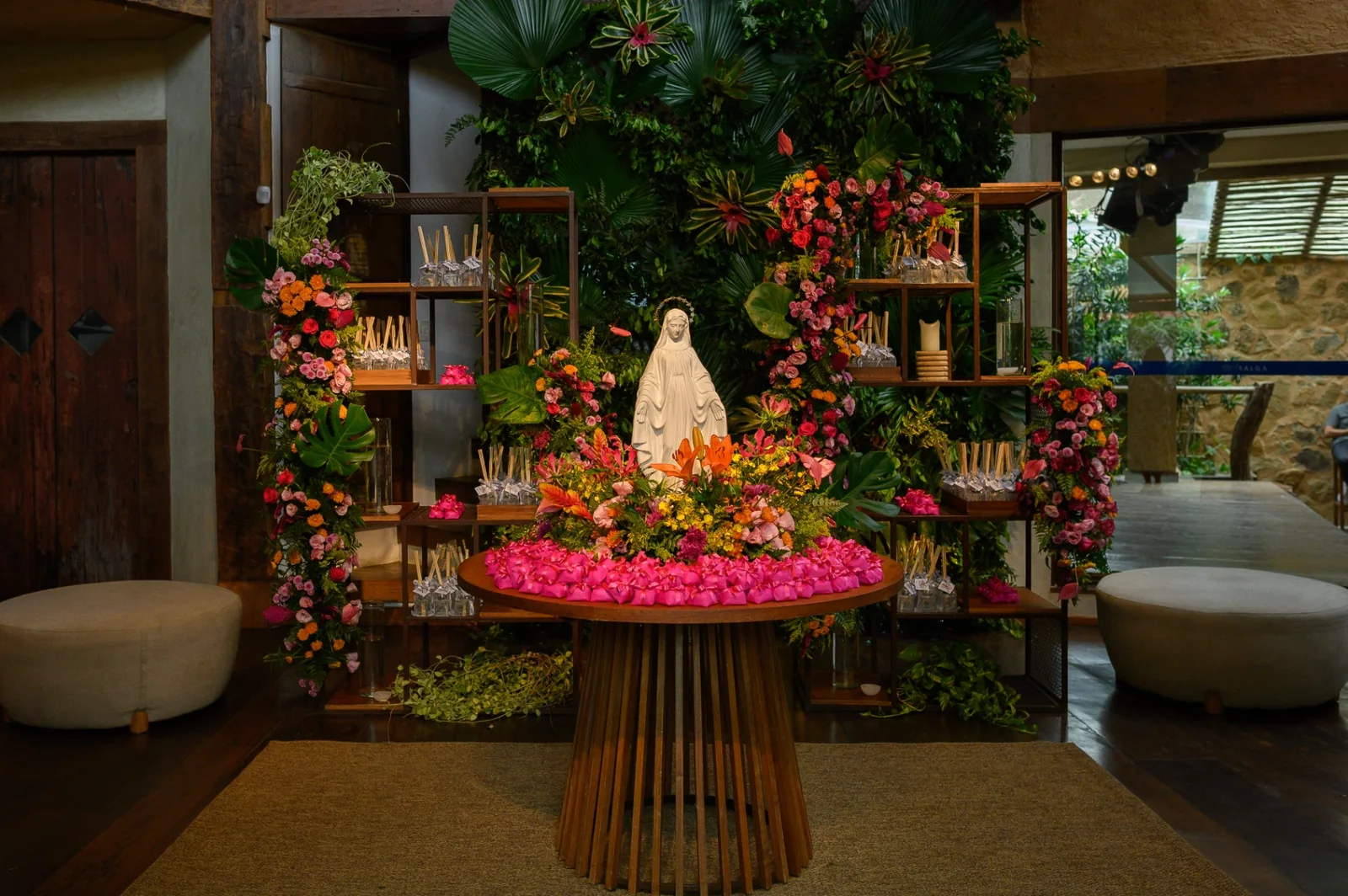 A tropical floral altar with an image of Our Lady and the sweets table.