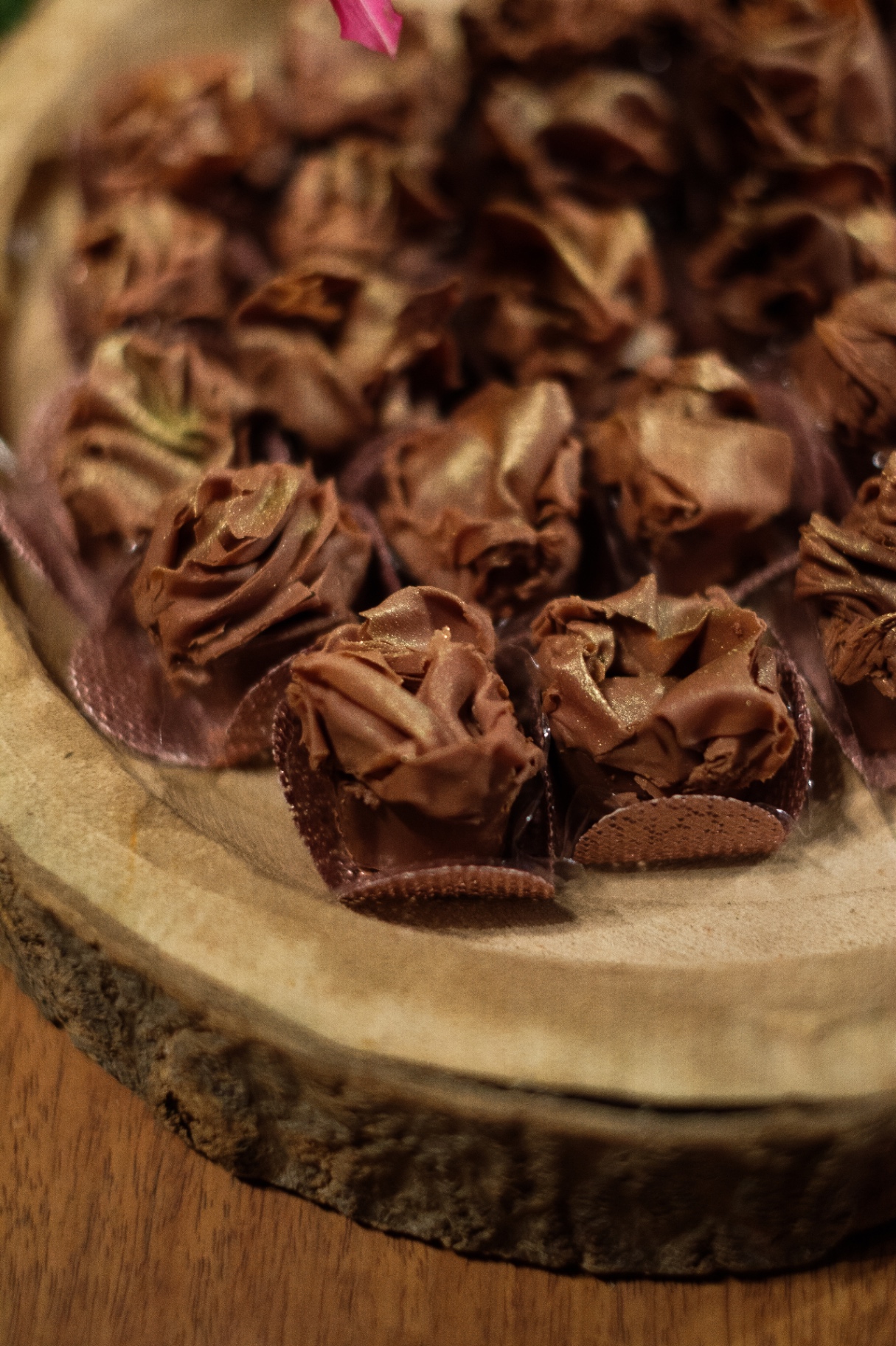 Brigadeiros gourmet em forminhas peroladas sobre madeira rústica
