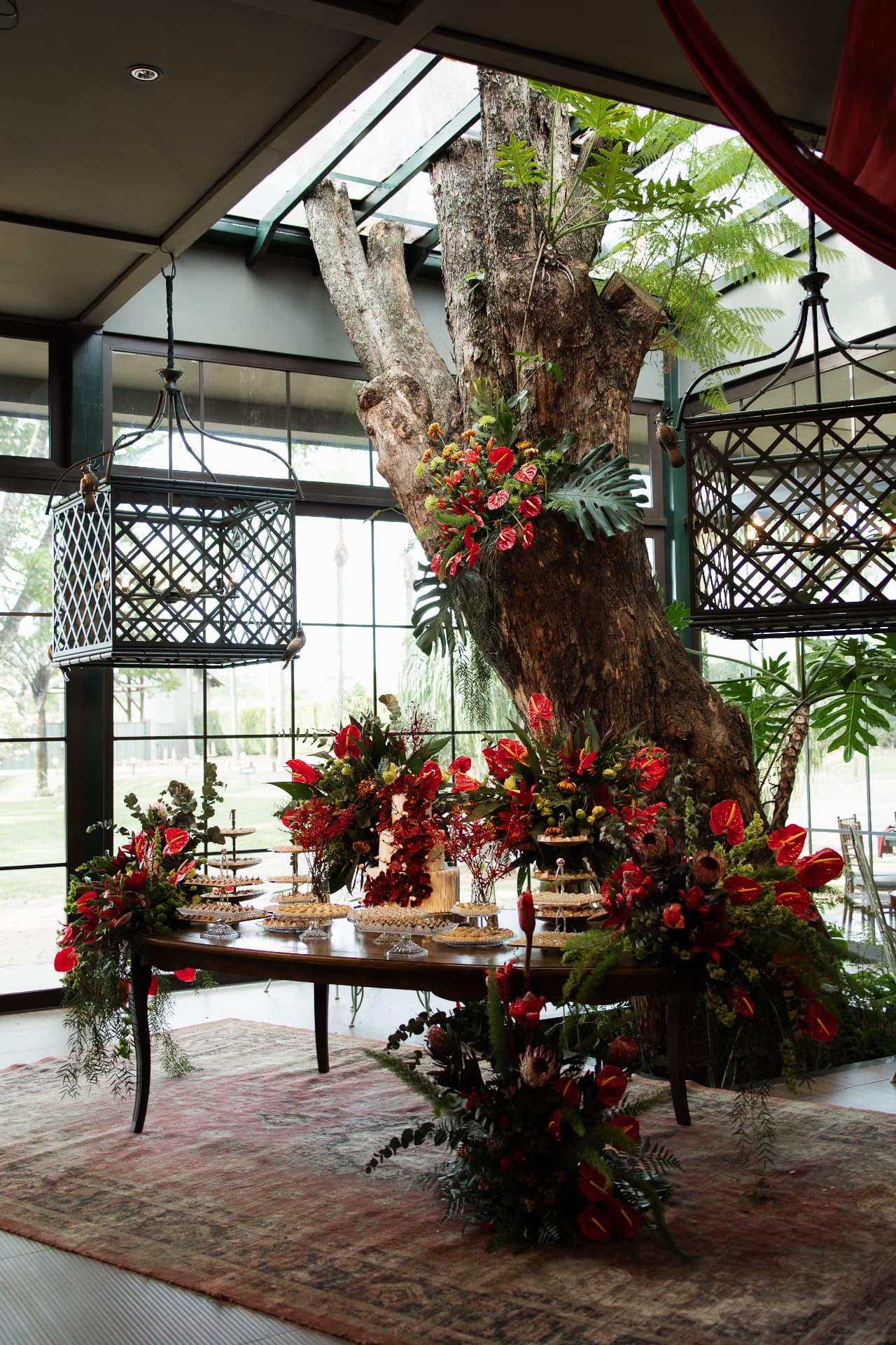 Lebbeke dessert table under a tree with red flowers at Malu and Leonardo's wedding