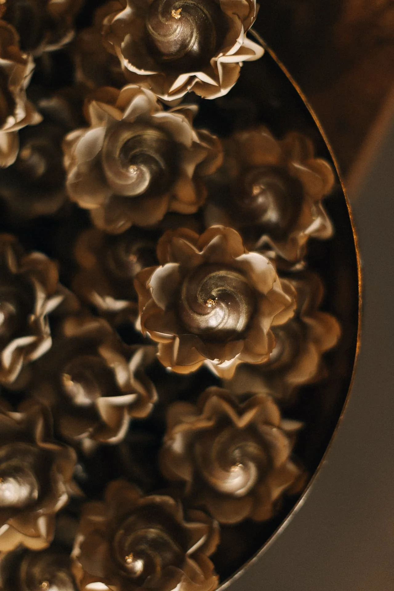 Detalhe artesanal de doces em forminhas elegantes, em tons dourados, para a Edição Nº 004 do Observatório Lebbeke