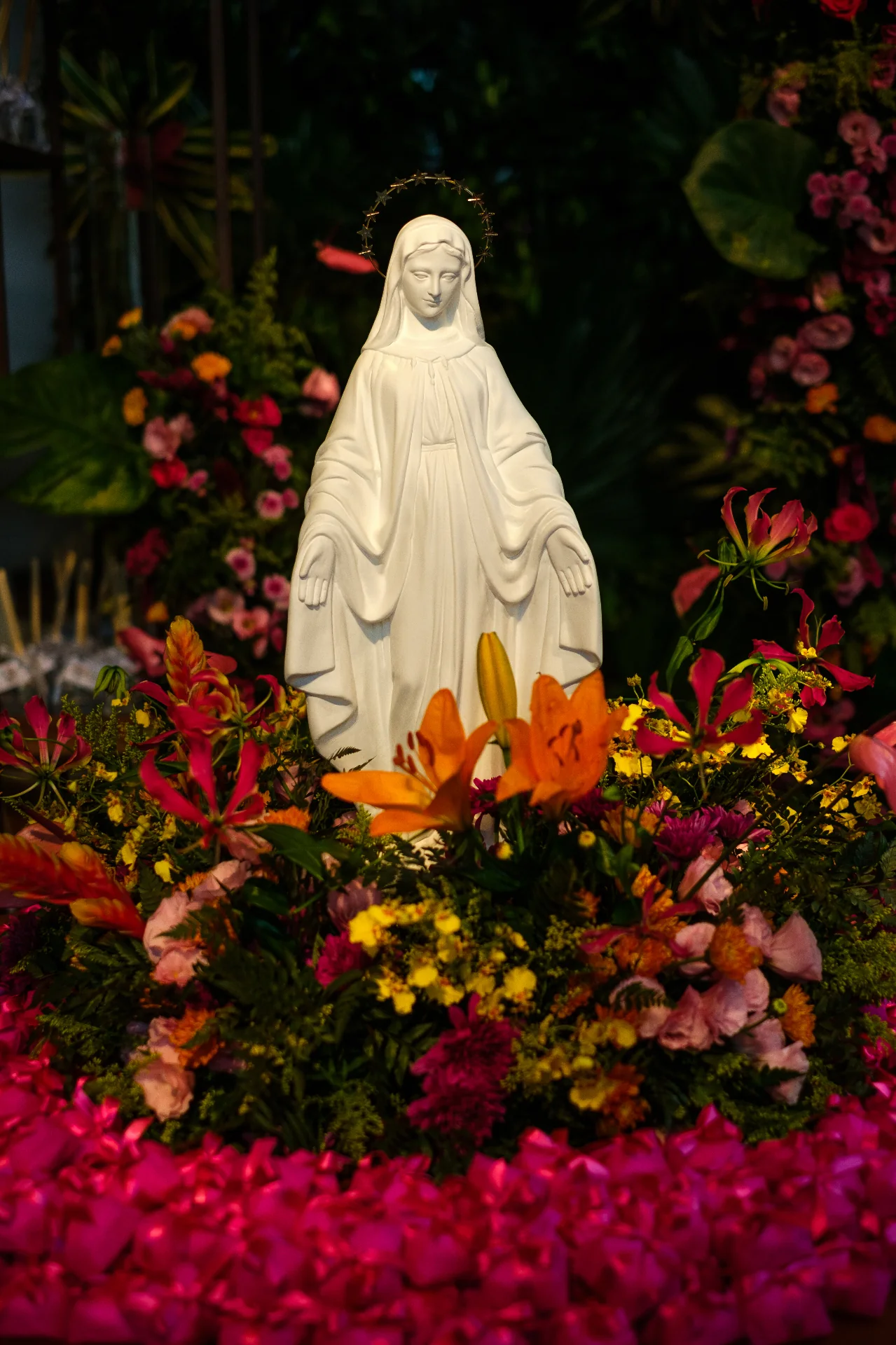 An image of Our Lady surrounded by colorful flowers.