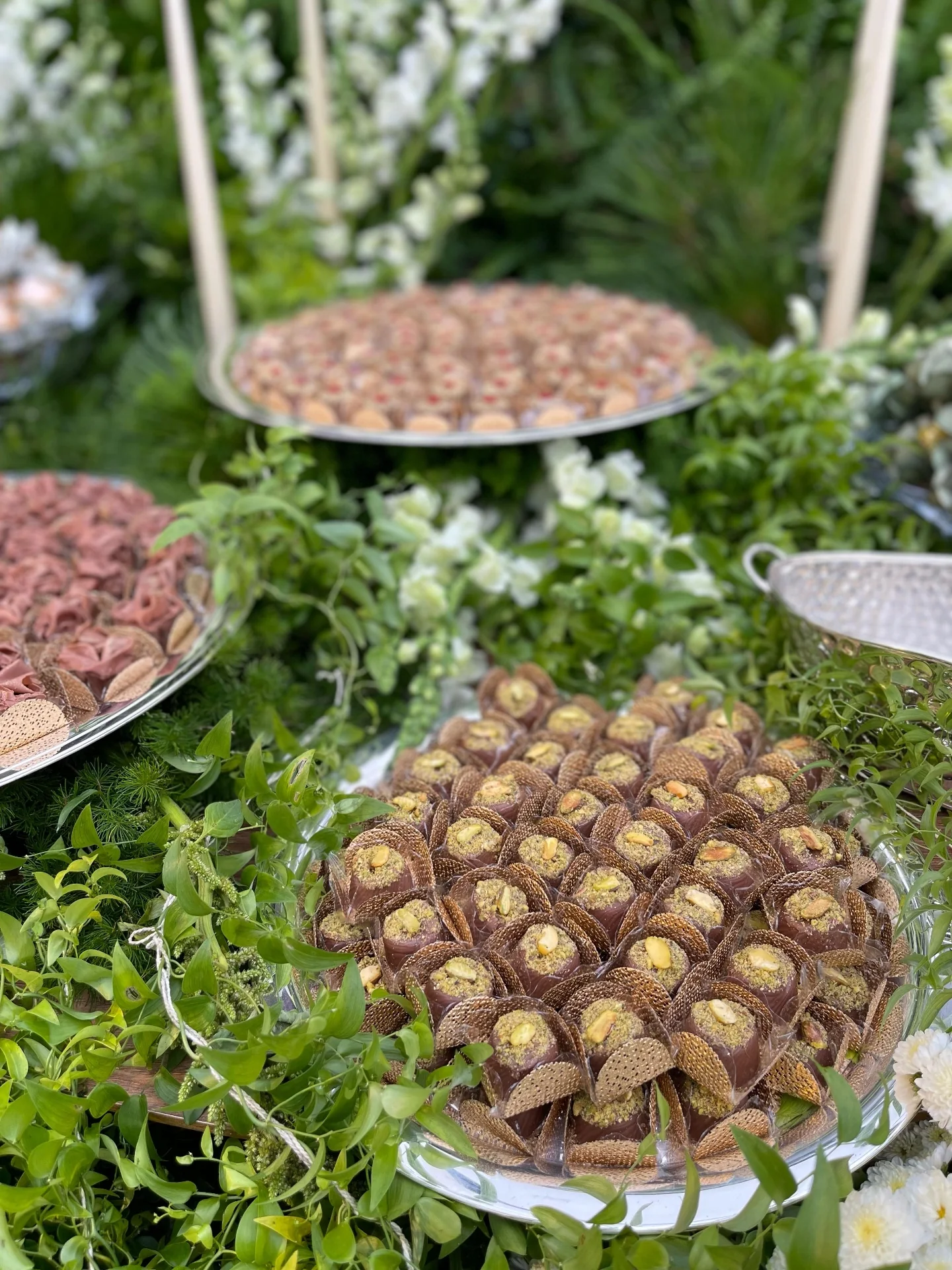 Pistachio bonbons and assorted sweets nestled among flowers.